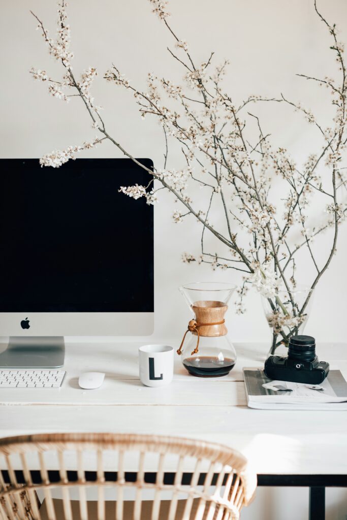 Computer desktop next to a beautiful floral display, for a blog post containing 3 questions to ask before hiring an interior designer. 